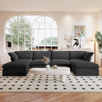 A black U-shaped linen 6-seat sectional sofa with a storage ottoman situated in a bright room with large windows, alongside a low coffee table with items on it.
