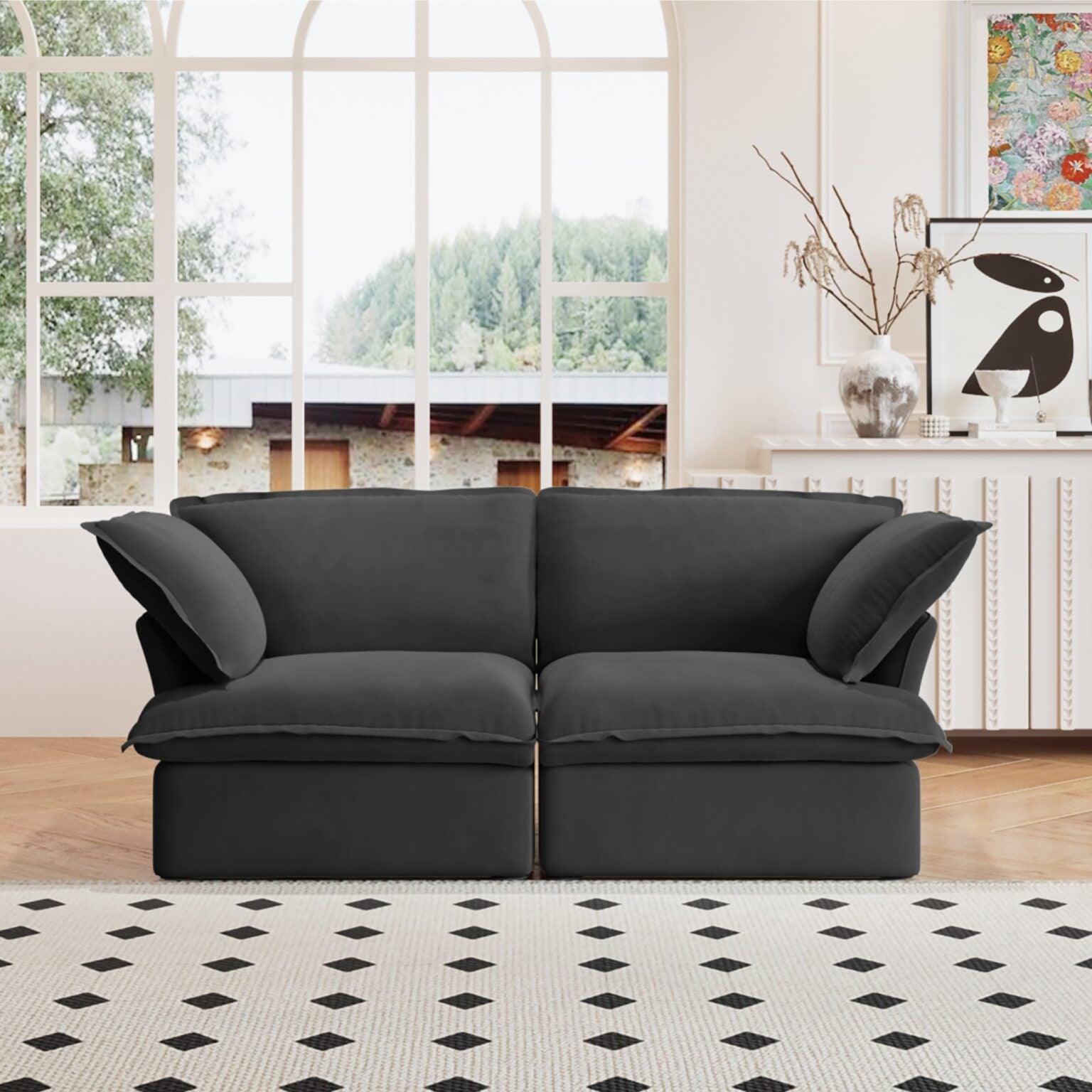 A black loveseat linen sectional sofa with modular design placed on a patterned rug in a bright living room setting.