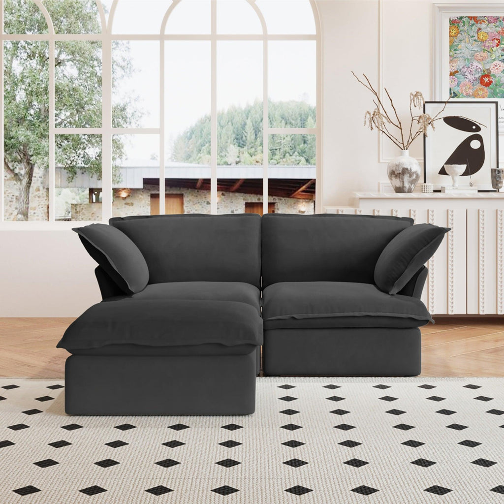 A black chaise lounge loveseat linen sectional sofa with a modular design and a storage ottoman, placed on a patterned rug in a bright living space.