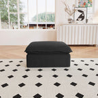 A black linen sectional ottoman with storage compartment placed on a black and white patterned rug in a living room setting.