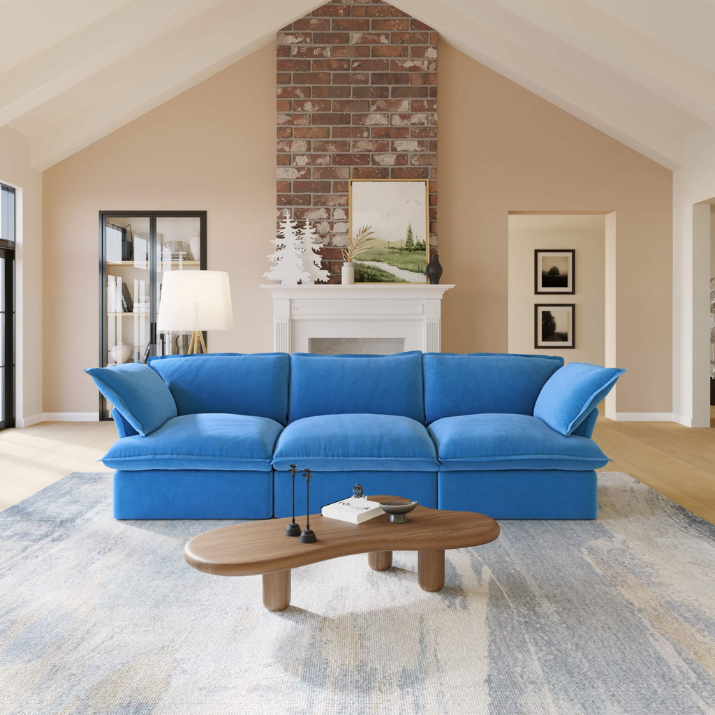 Blue 3-seat sofa in a living room with a wooden coffee table and decorative items.