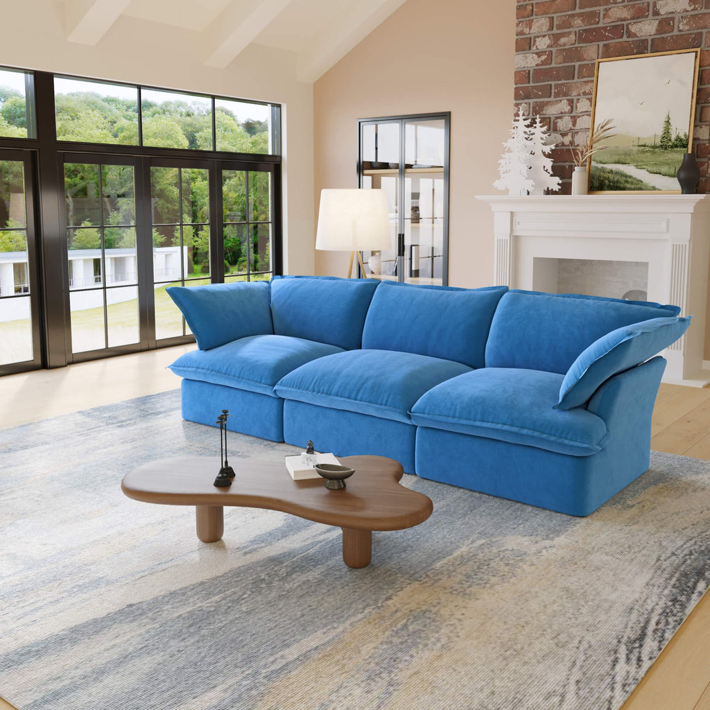 Blue 3-seat sofa in a living room with a coffee table and large windows.