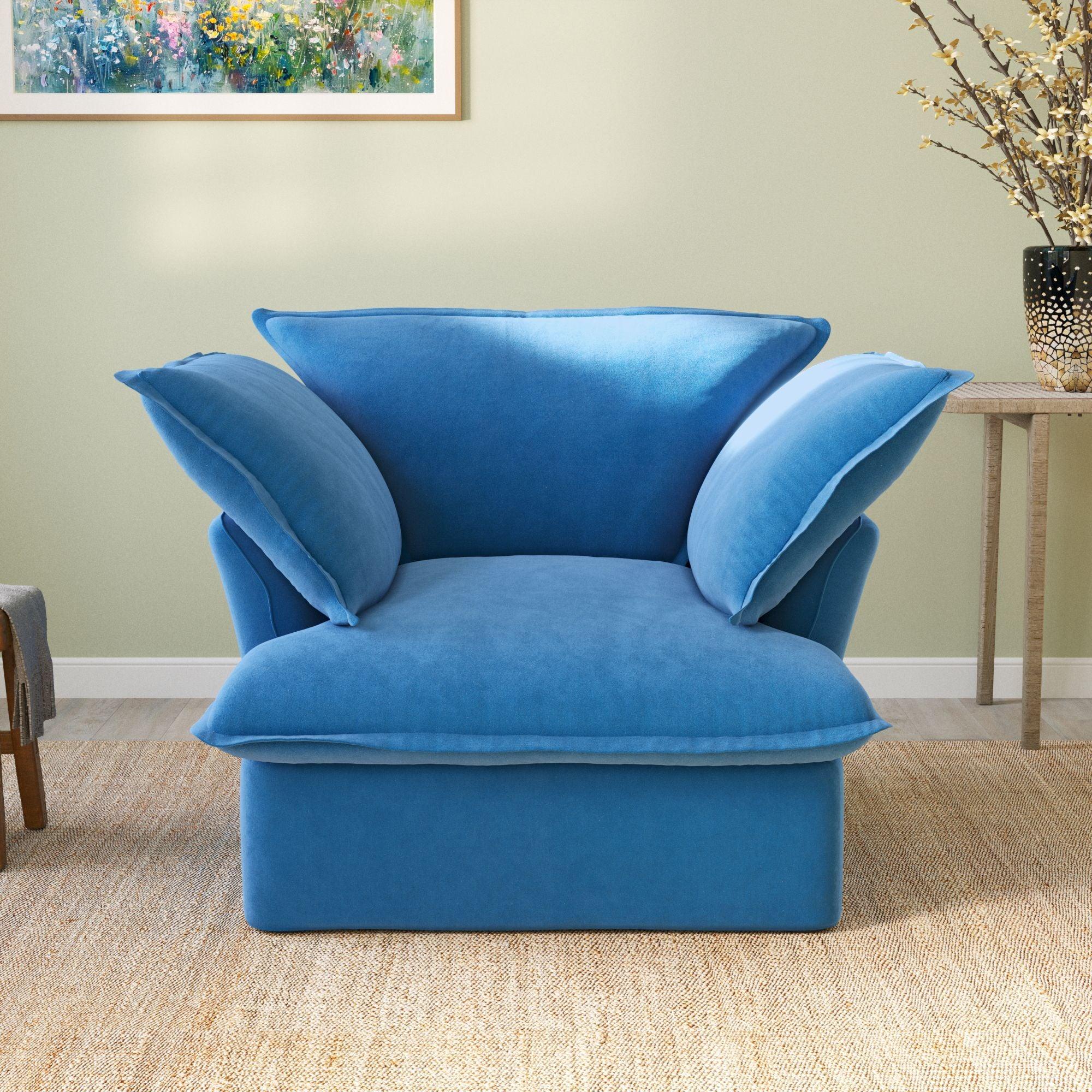 A plush blue velvet modular sectional sofa in a cozy living room setting, with a cushioned backrest and seat.