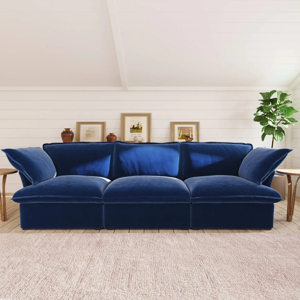 Dark blue 3-seater velvet sofa in a living room setting with a neutral color palette.