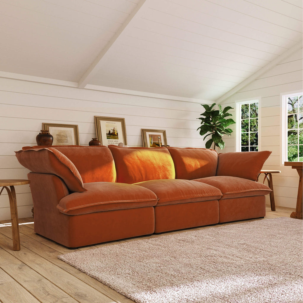Dark orange sectional sofa in a room with wooden floors and white walls.