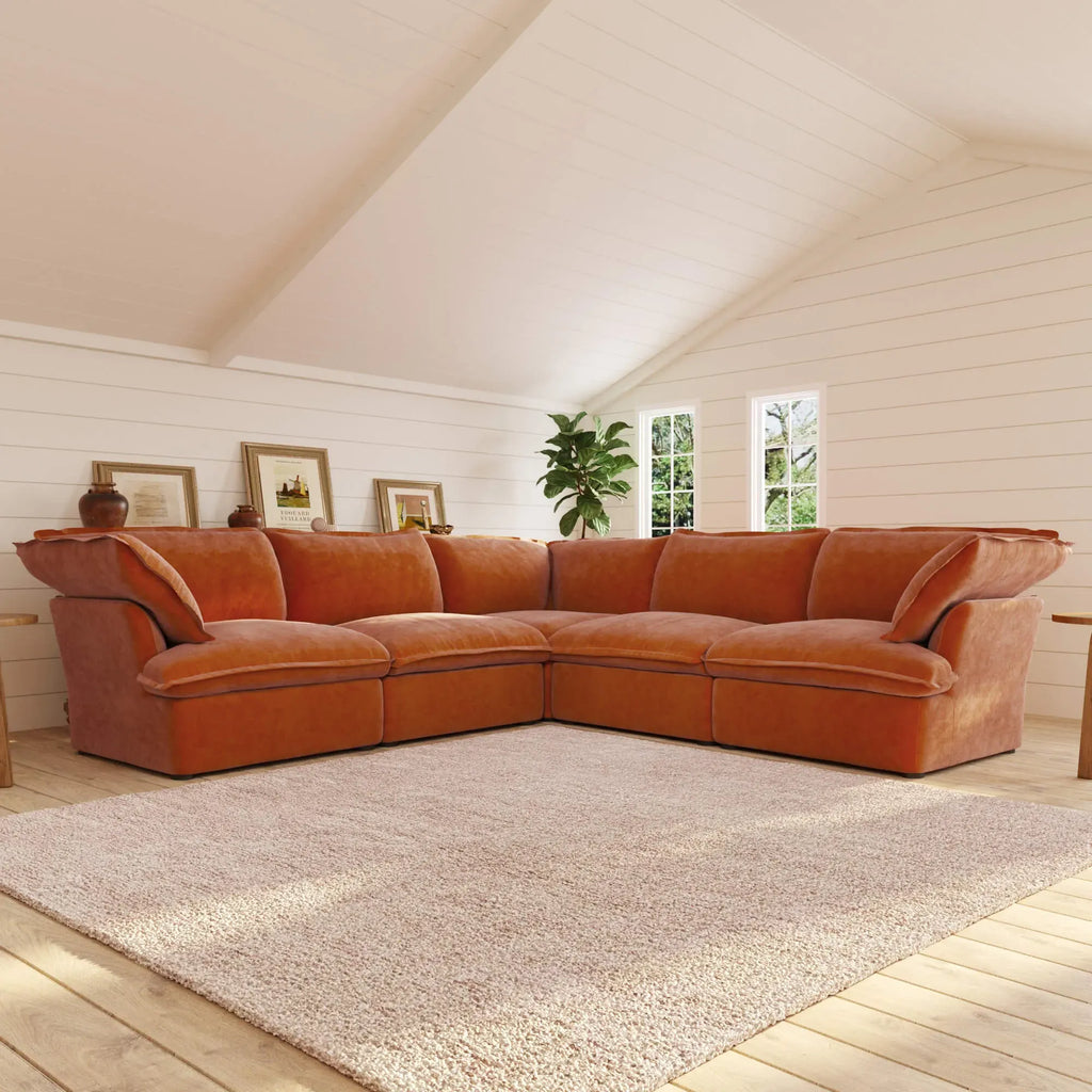 Dark orange corner sectional sofa in a living room with white walls and a rug.