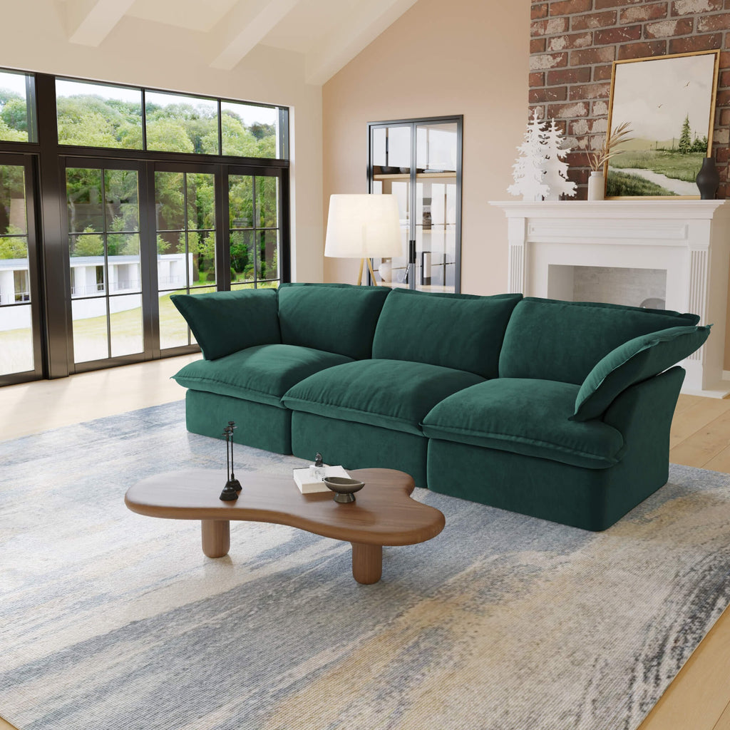 Green 3-seater sofa in a living room with a coffee table and large windows.