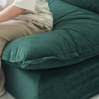 Person sitting on a sofa cushion of an green sofa to show its softness