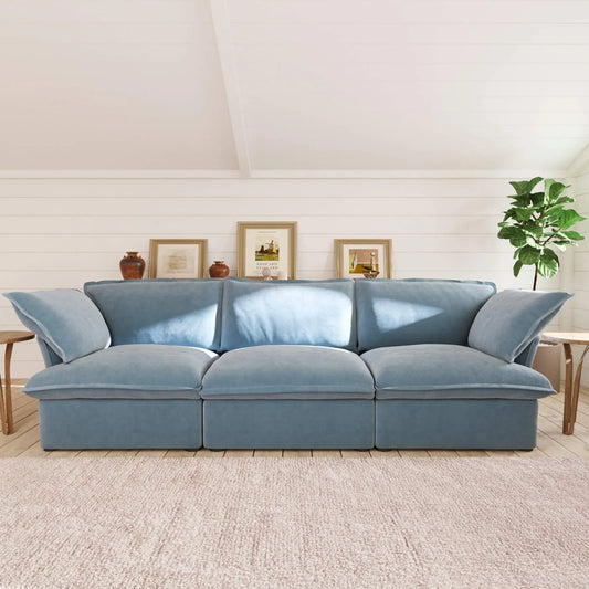 Light blue 3-seater sofa in a living room with framed pictures and a plant.
