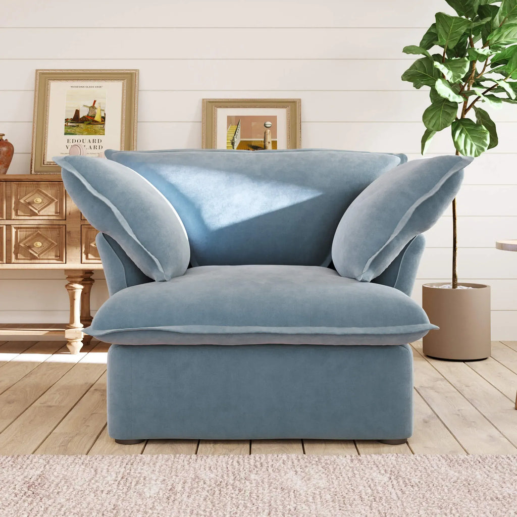 Light blue armchair in a living room setting with a plant and framed pictures on the wall.