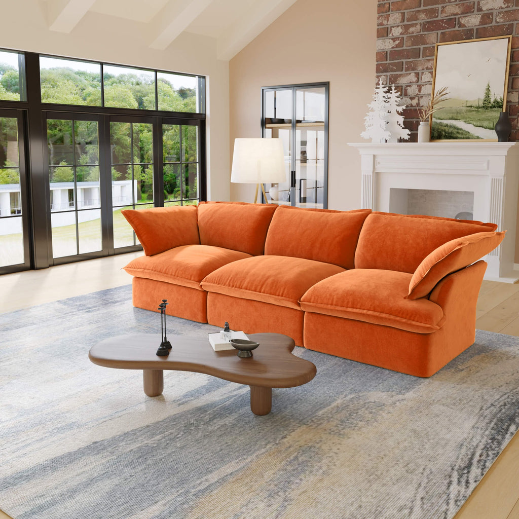 Orange 3-seat sofa in a living room with large windows and a fireplace.