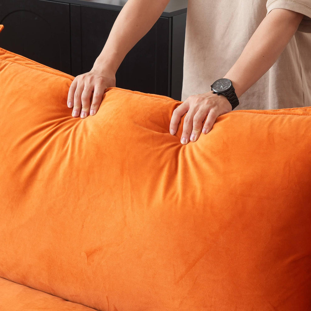Person pressing on the back cushion of an orange sofa to show its softness