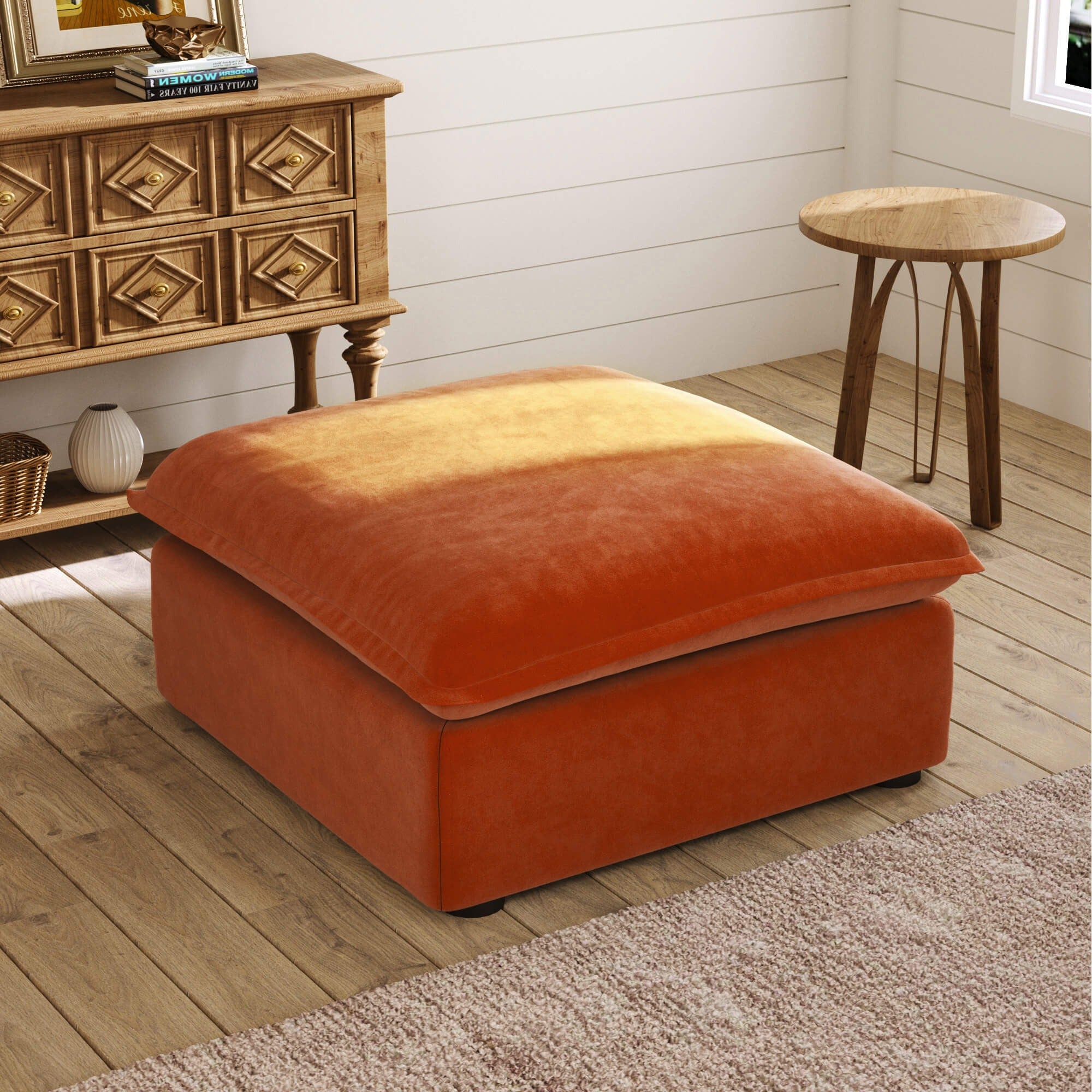 Orange ottoman in a room with wooden furniture and a white wall.