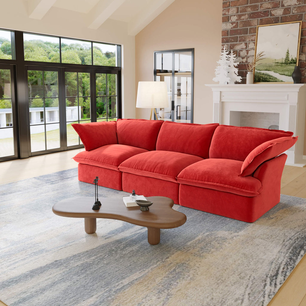 Red 3-seat sofa in a living room with large windows and a fireplace.
