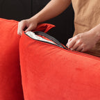 Person unzipping a cushion cover of a red sofa