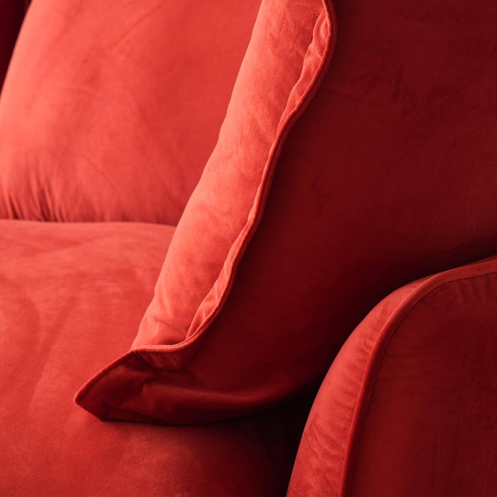 Close-up of the right seat and armrest pillow of a red velvet sofa