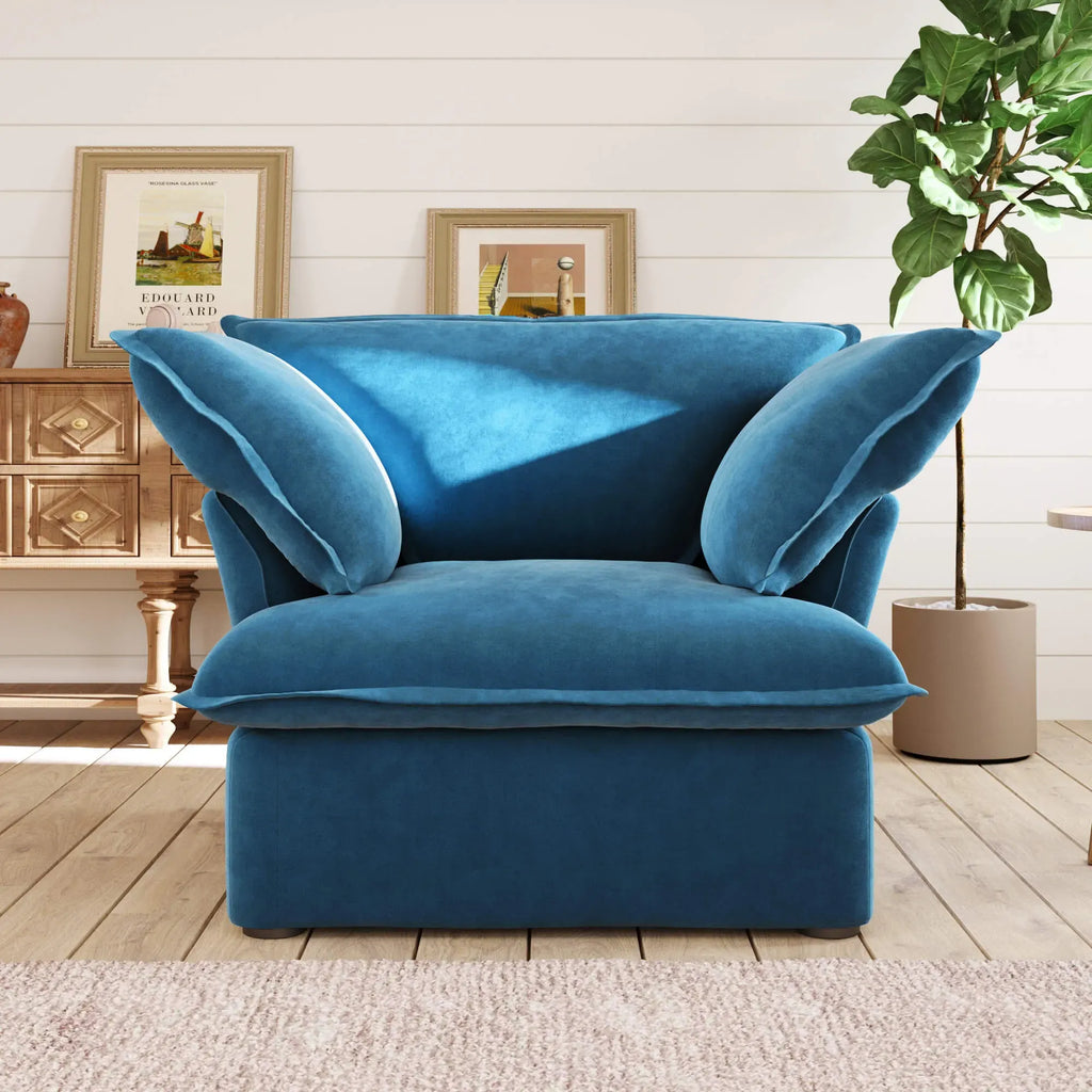 Sky blue armchair in a living room setting with a plant and wooden cabinet.