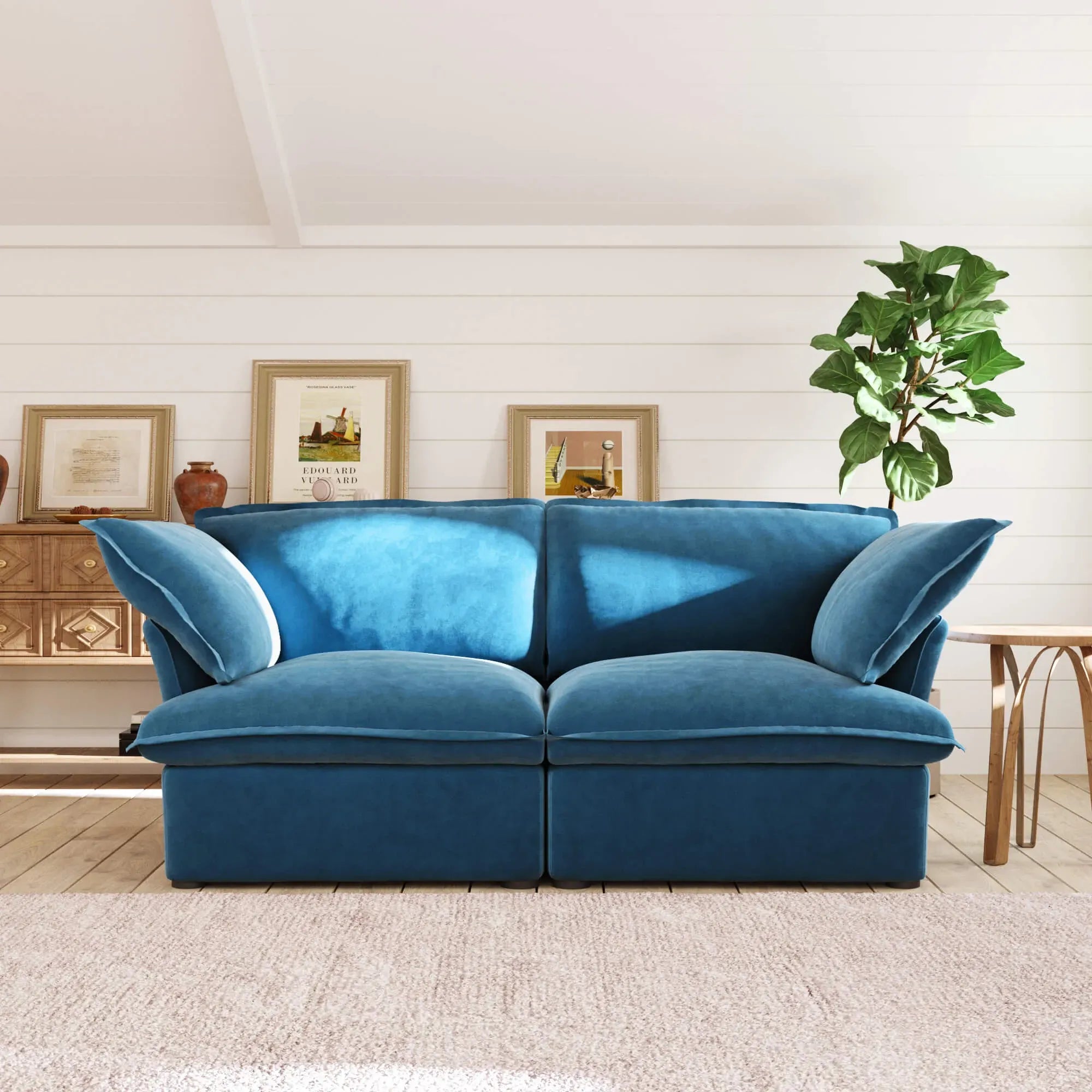 Sky blue loveseat sofa in a living room with a plant and framed pictures on the wall.