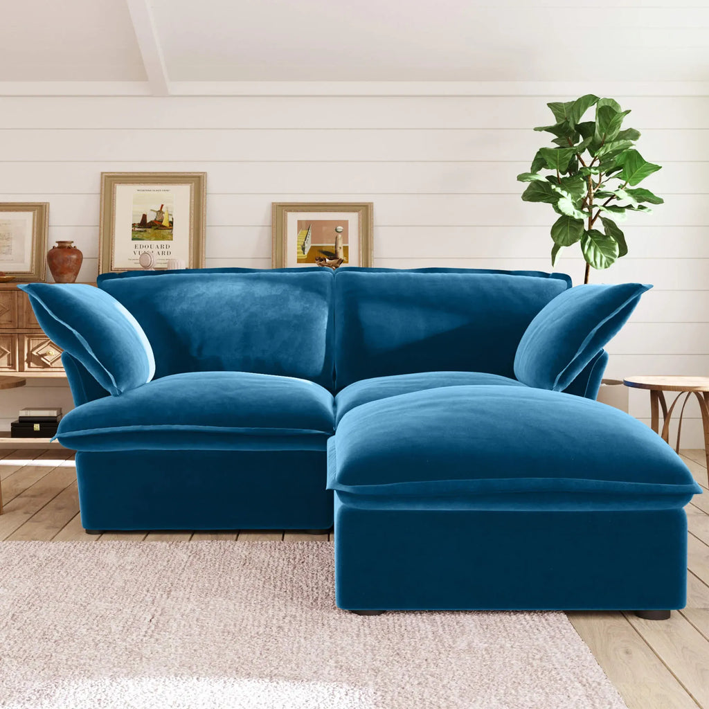 Sky blue velvet sectional loveseat sofa with ottoman in a living room setting with decor elements.