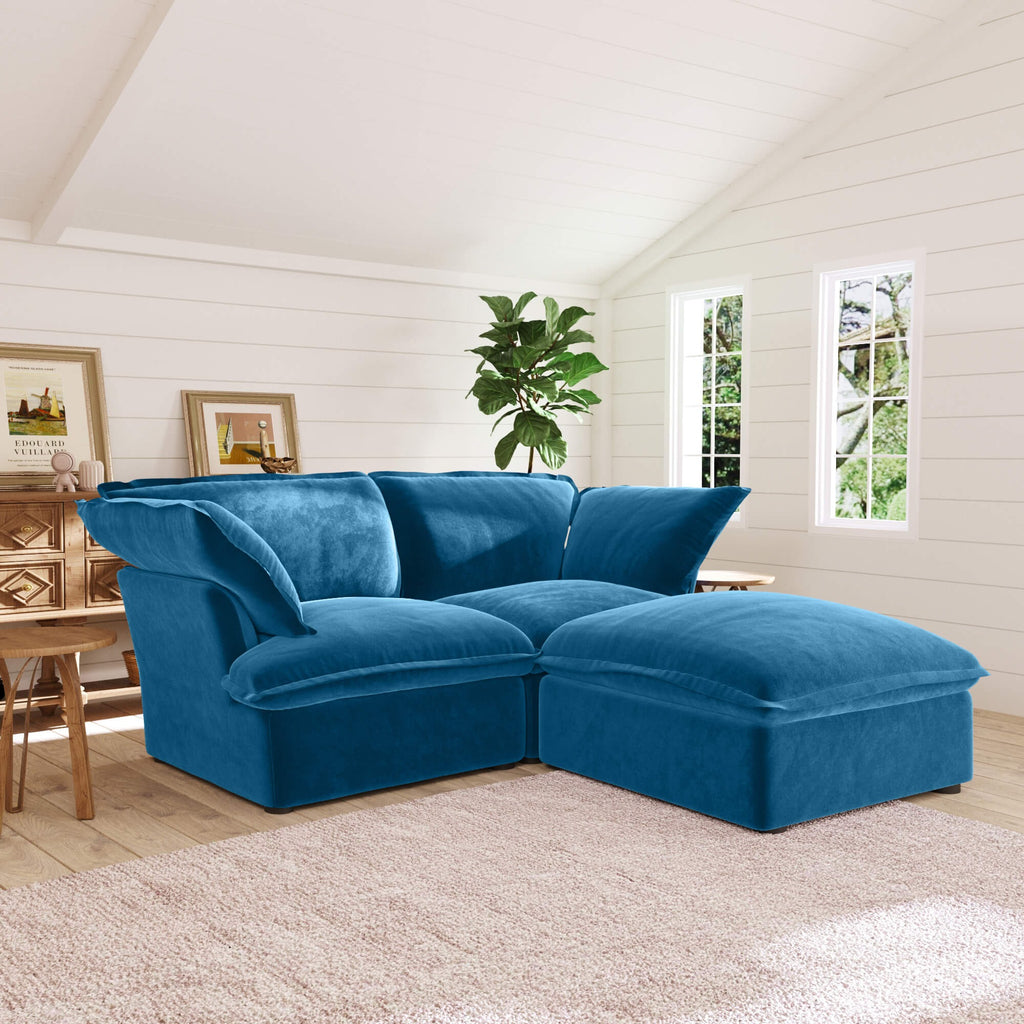 Sky blue sectional loveseat sofa with ottoman in a living room with wooden furniture and plants.