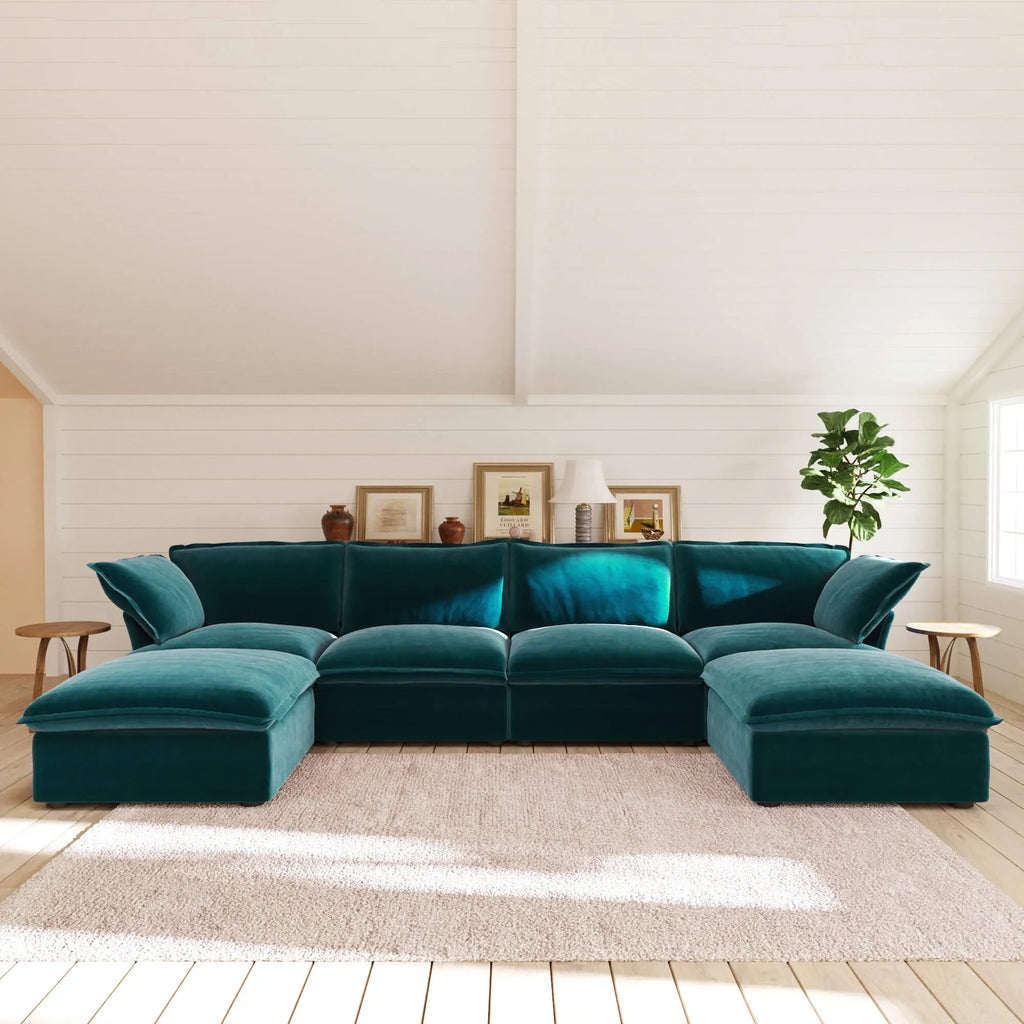 Teal U-shaped sectional sofa in a living room with white walls and wooden floor.