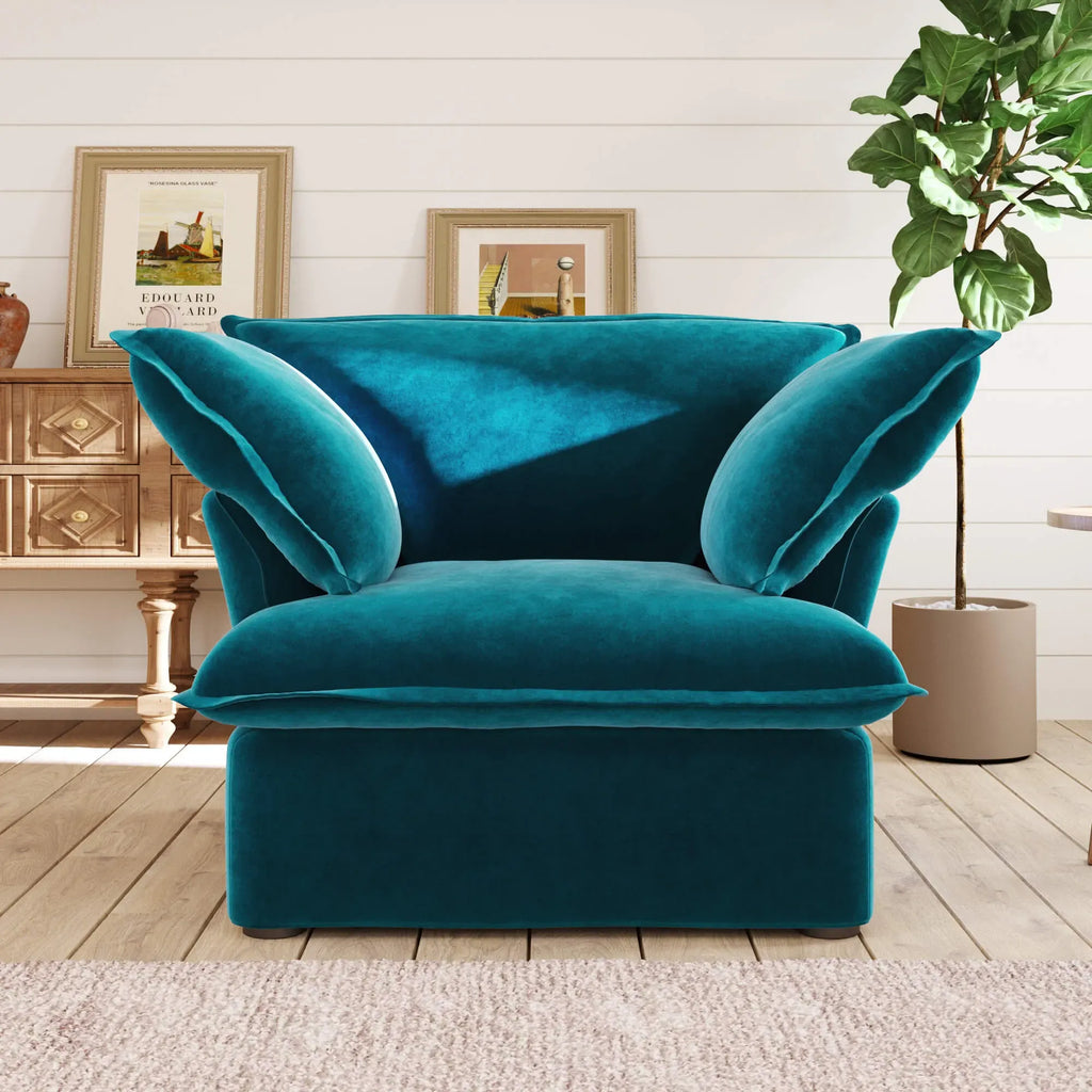 Teal armchair in a living room setting with a wooden cabinet and plant.