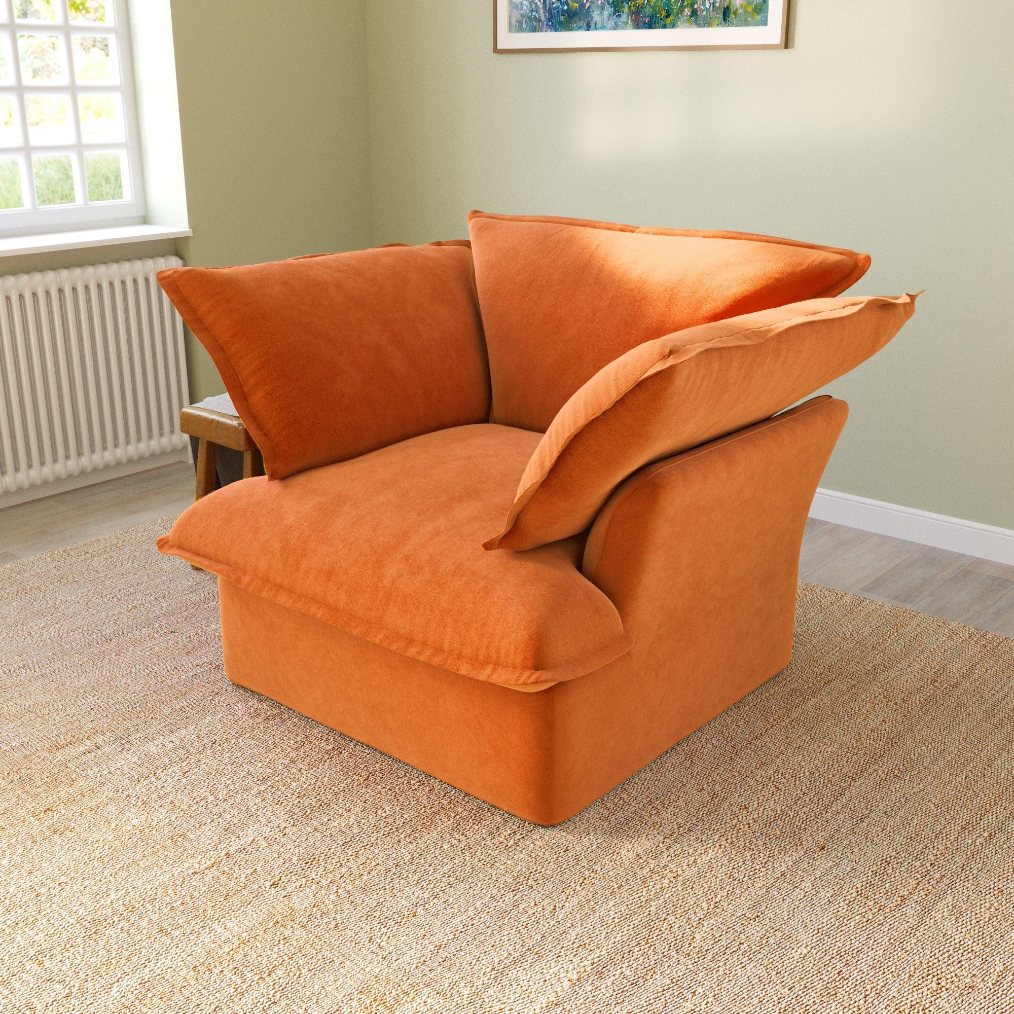 An orange velvet accent chair with a cushioned backrest and seat, placed in a room with a light green wall and a framed picture on the wall.