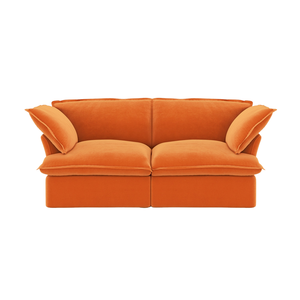 Orange velvet sofa with flared armrests on a white background