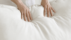 Person pressing on a white linen back cushion of a sofa