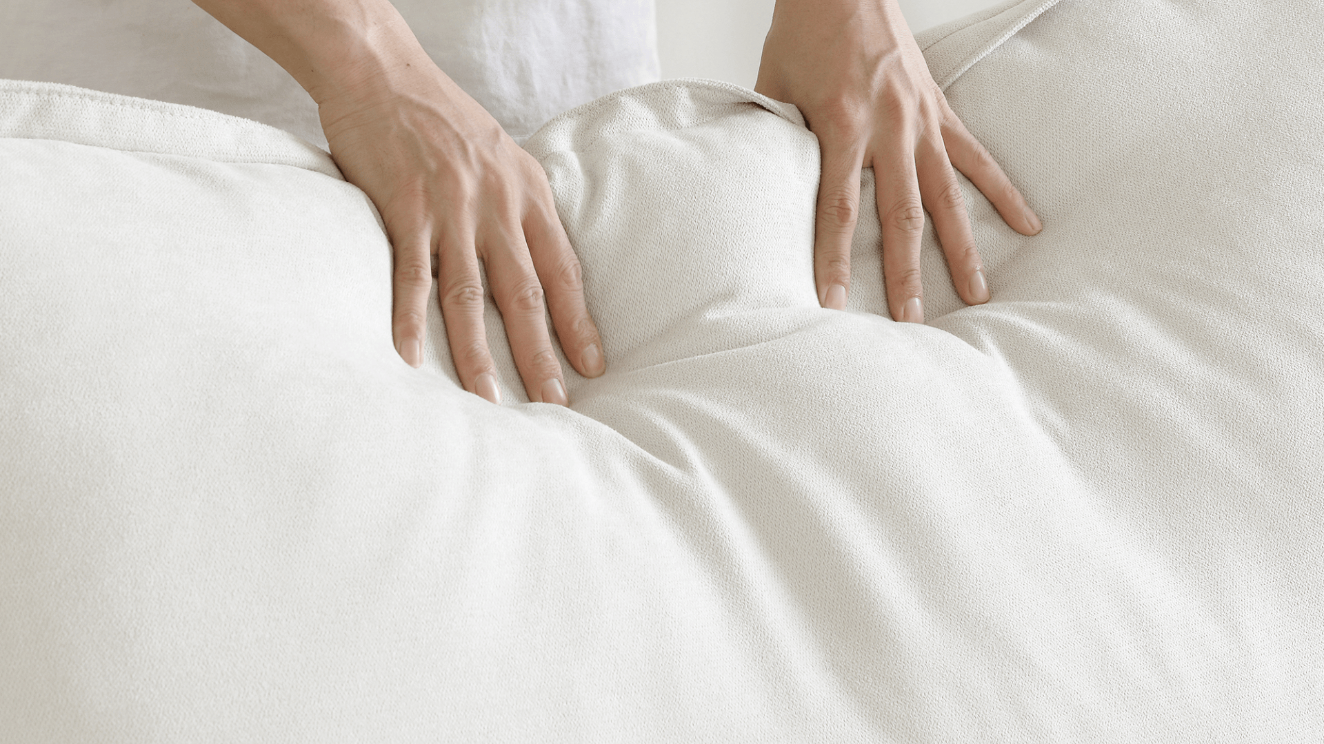 Person pressing on a white linen back cushion of a sofa