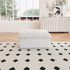 A white linen sectional ottoman with storage compartment placed on a black and white patterned rug in a living room setting.