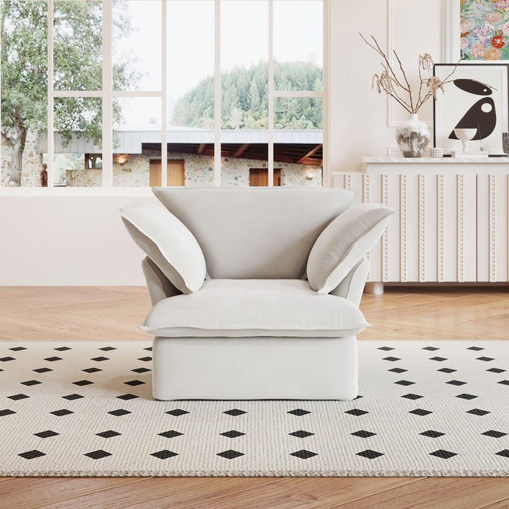 A white linen armchair with a solid frame and washable covers, placed on a patterned rug in a bright room.