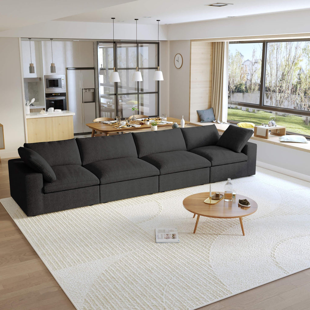 A modern black sectional sofa in a living room setting, featuring a 4-seater configuration with a modular design, down-filled cushions.