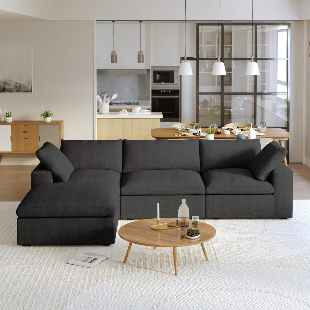 A black L-shaped modular sectional sofa with a storage ottoman in a modern living room setting.