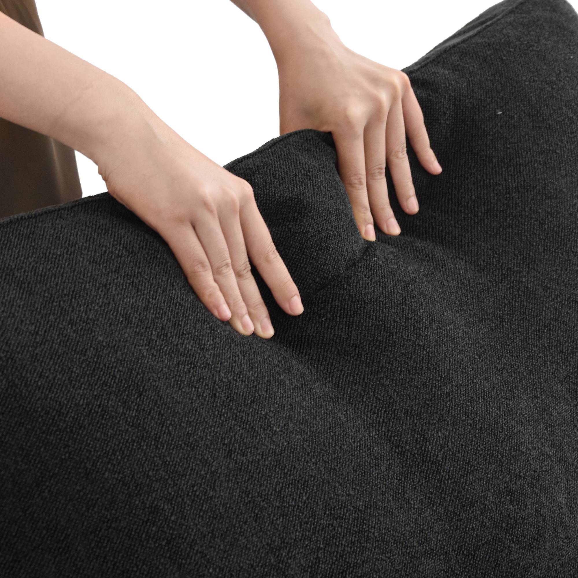 Person squishing a backrest cushion of a black sofa