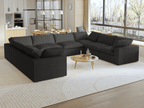 A modern, modular pit-style 8-seat sectional sofa in black in a living room setting with white cushions and a clean, contemporary design.