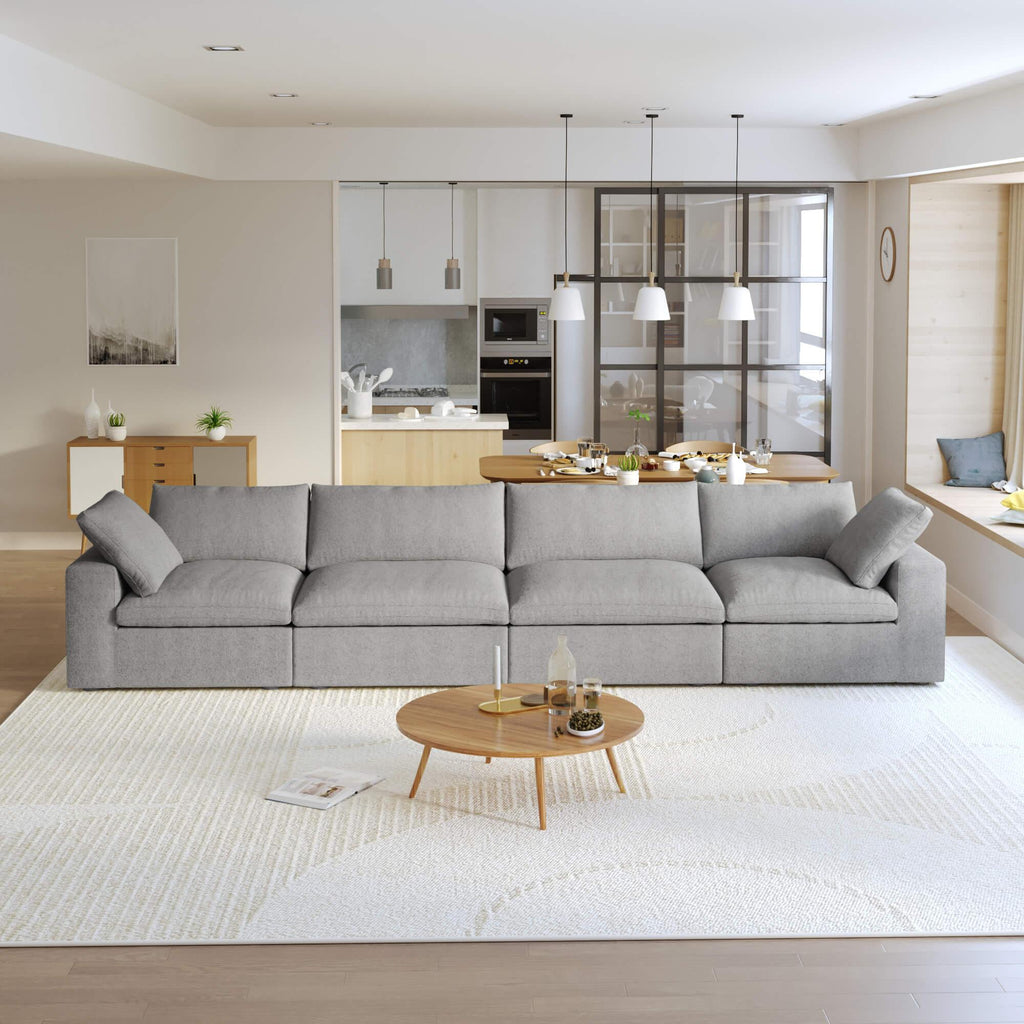 A modern gray sectional sofa in a living room setting, featuring a 4-seater configuration with a modular design, and down-filled cushions.