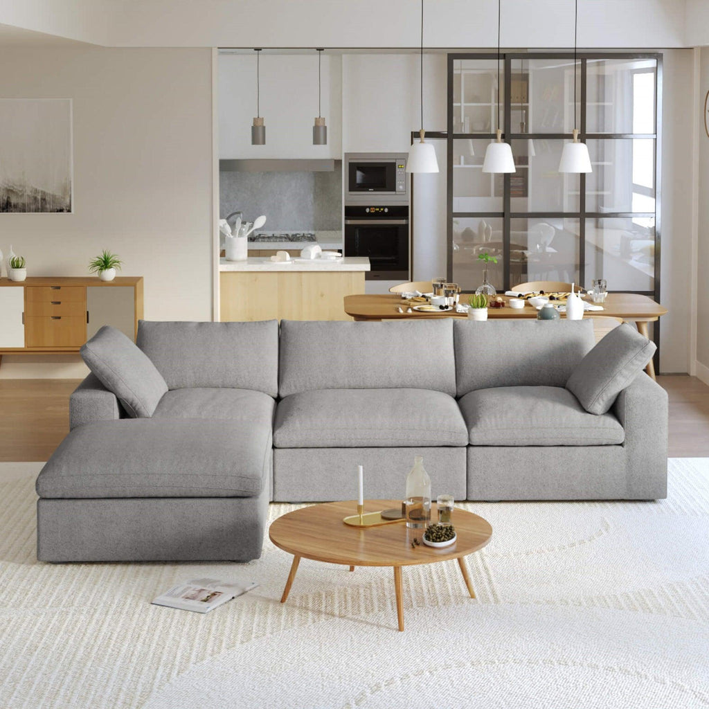 A gray L-shaped modular sectional sofa with a storage ottoman in a modern living room setting.