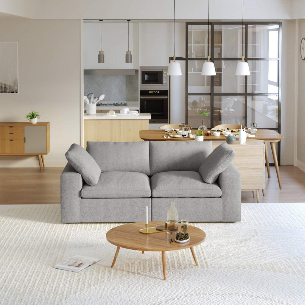 A modern gray loveseat sectional sofa in a bright living room setting, featuring a white slipcover, and designed for small space functionality.