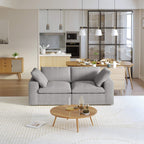 A modern gray loveseat sectional sofa in a bright living room setting, featuring a white slipcover, and designed for small space functionality.