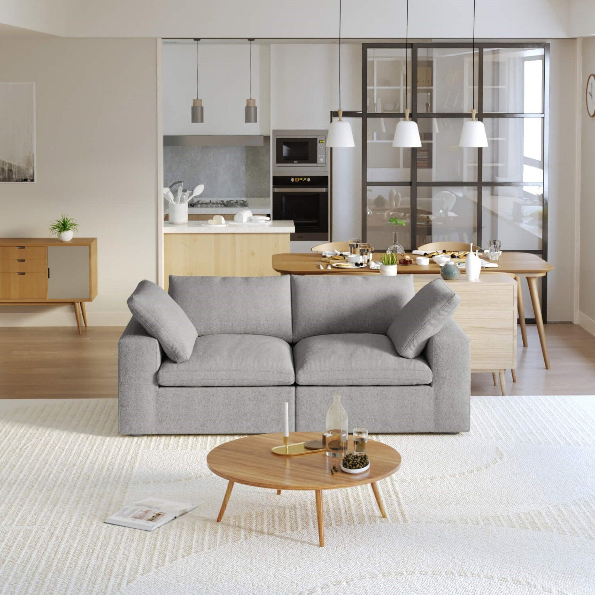 A modern gray loveseat sectional sofa in a bright living room setting, featuring a white slipcover, and designed for small space functionality.