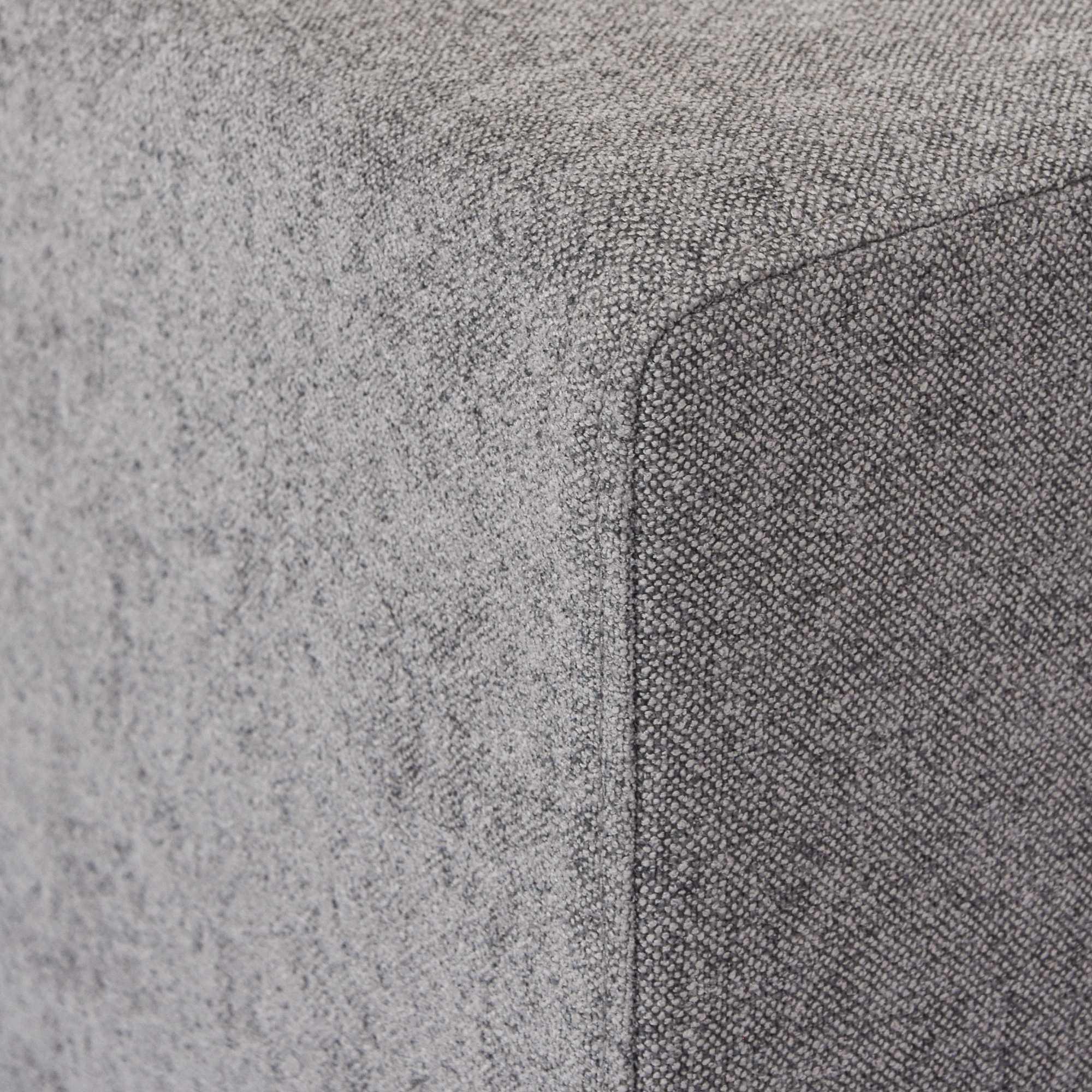 Close-up of a corner of an armrest of a gray sofa