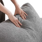 Person squishing a backrest cushion of a gray sofa to show its softness