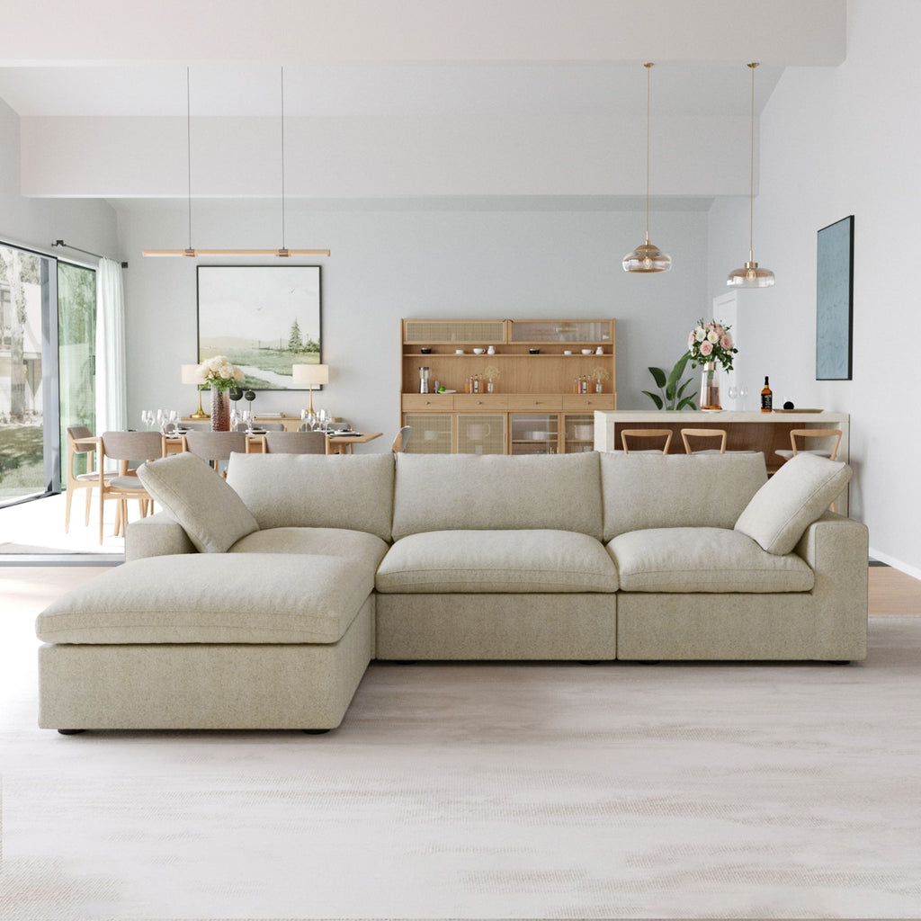 Khaki L-shaped sectional sofa with a storage ottoman in a modern living room with a kitchen in the background.