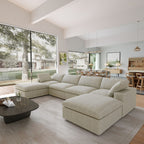 Modern living room with a khaki U-shaped sectional sofa, coffee table, and large windows.