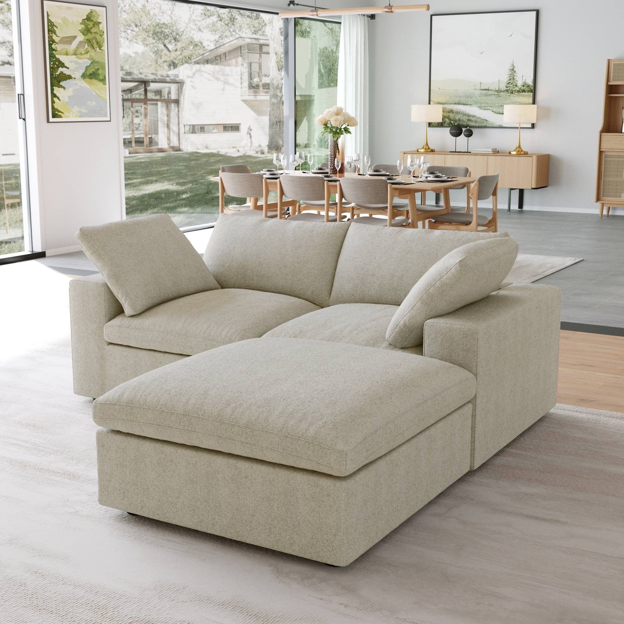 Khaki loveseat sectional sofa with a storage ottoman in a modern living room with large windows and a dining area.