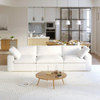 A modern white 3-seater sectional sofa in a living room setting with a round wooden coffee table in front and a kitchen area in the background.