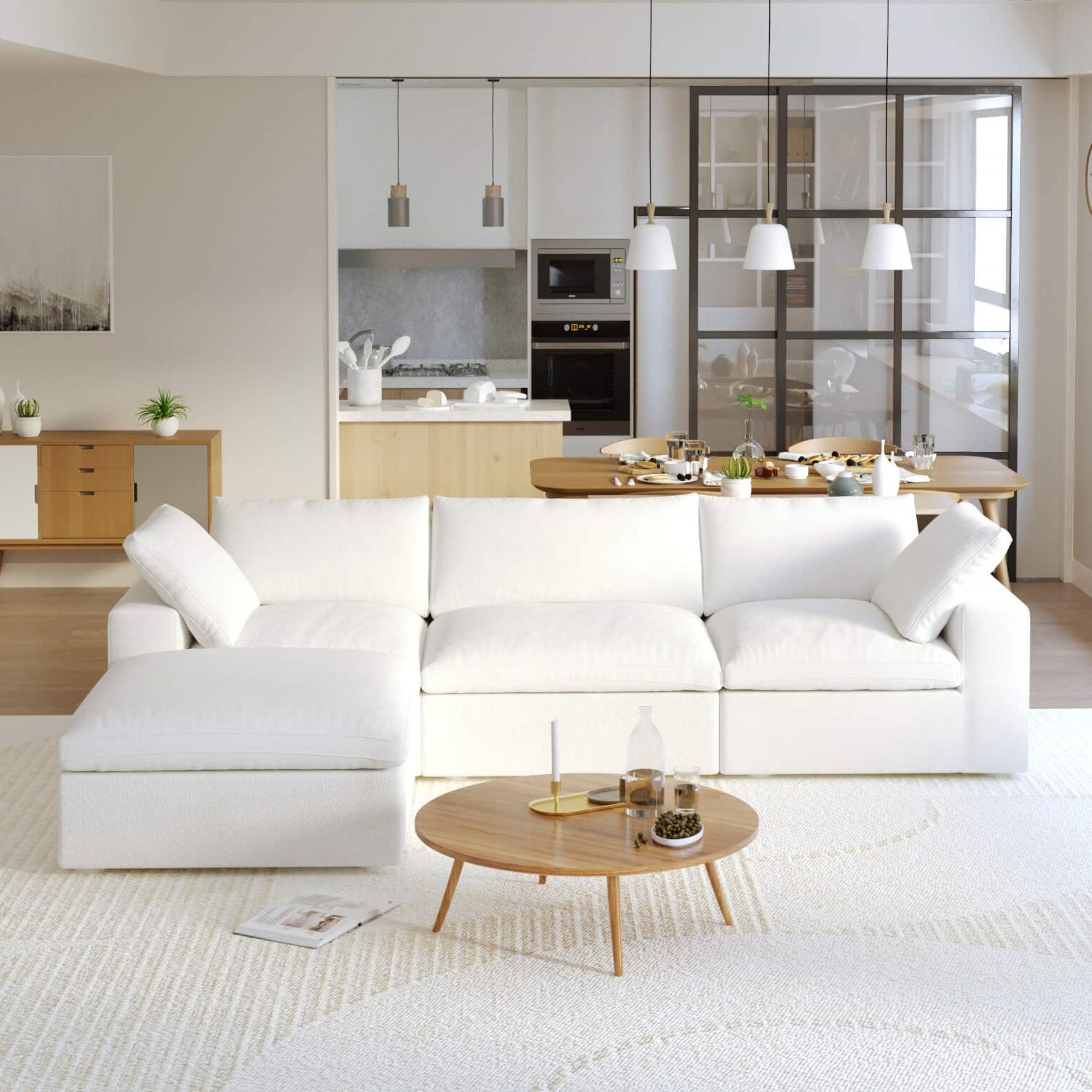 A white L-shaped modular sectional sofa with a storage ottoman in a modern living room setting.