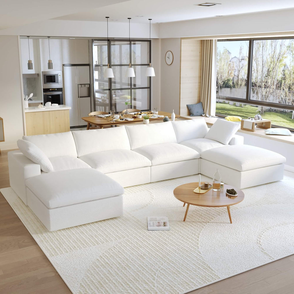 A large, U-shaped, white modular sectional sofa with storage ottoman in a modern living room setting.