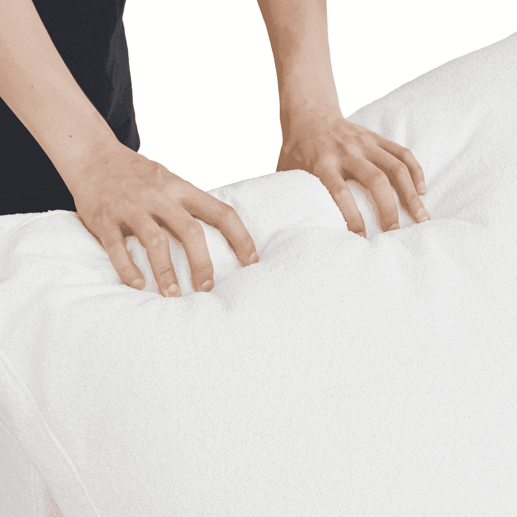 Person squishing a backrest cushion of a white sofa to show its softness